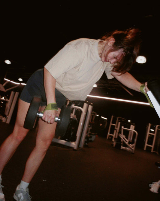 woman doing single arm exercise wearing uppper lifting straps